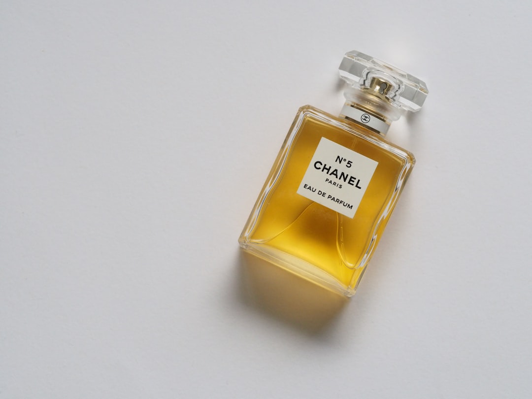 A close-up of a person applying perfume on their wrist with a stylish bottle in the background.